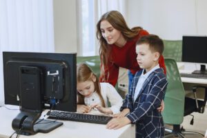 teacher working with two students on computer