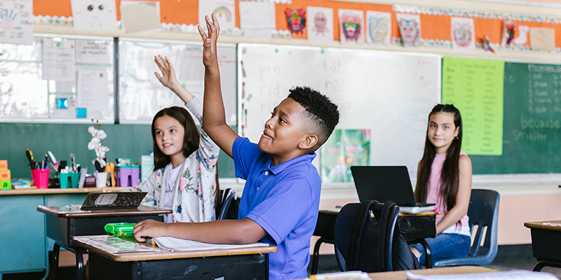 students raising hands in classroom