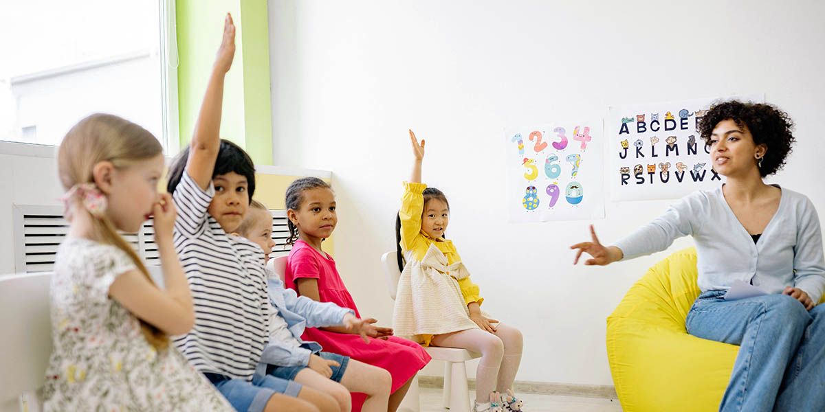 student raising hand with teacher in classroom