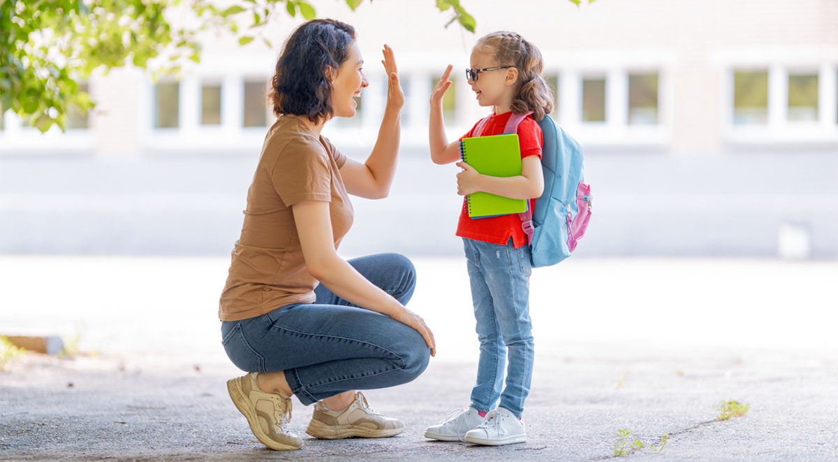 student and parent high fiving outside of school